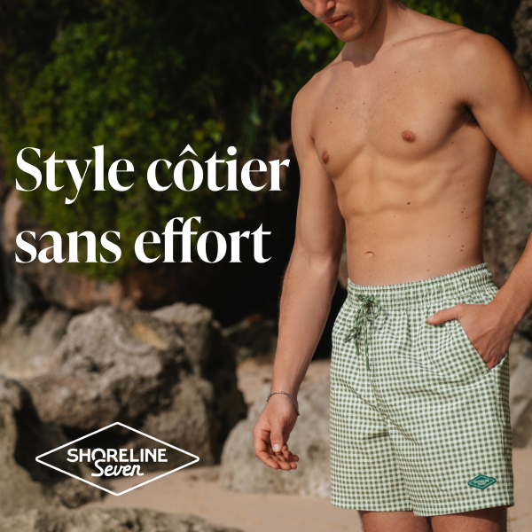 Homme sur la plage avec une main dans la poche d’un maillot au motif à carreaux vert et blanc de la marque Shoreline Seven.