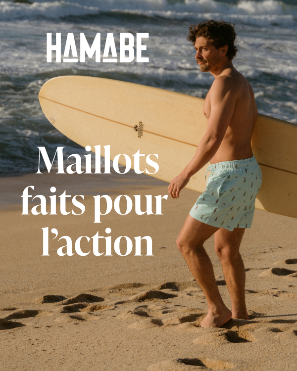 Homme sur la plage qui porte entre ses mains une planche de surf et portant un maillot de bain Hamabe.