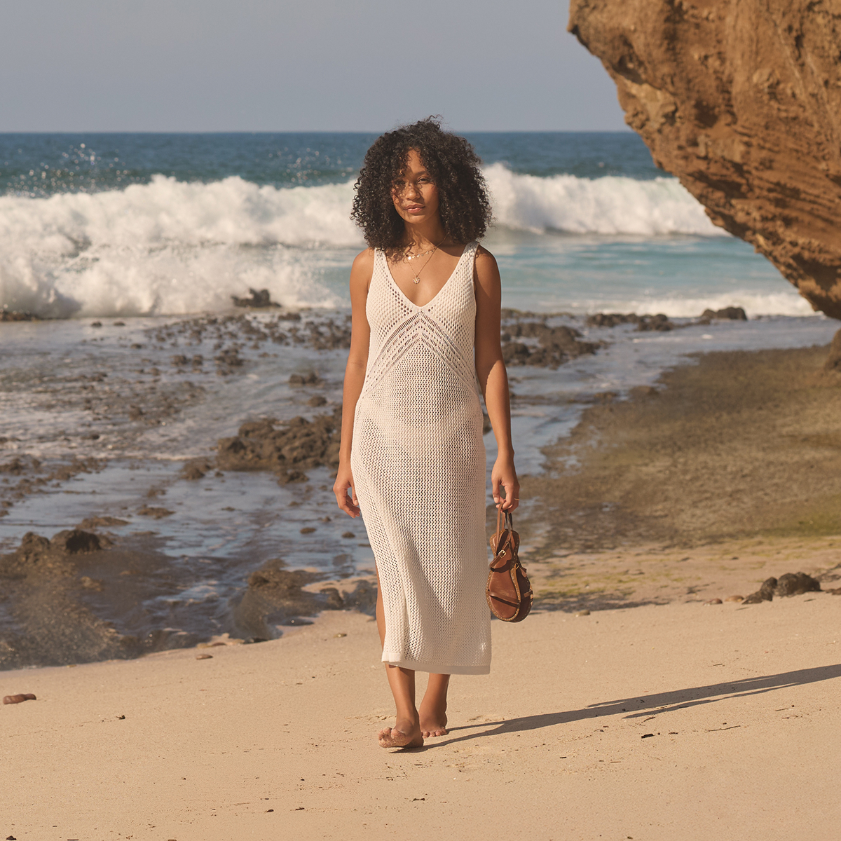 Femme portant une robe en crochet blanche par MyBikiniStory, marchant sur la plage – Bikini Village 