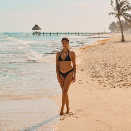 Une femme sur la plage, portant un bikini noir